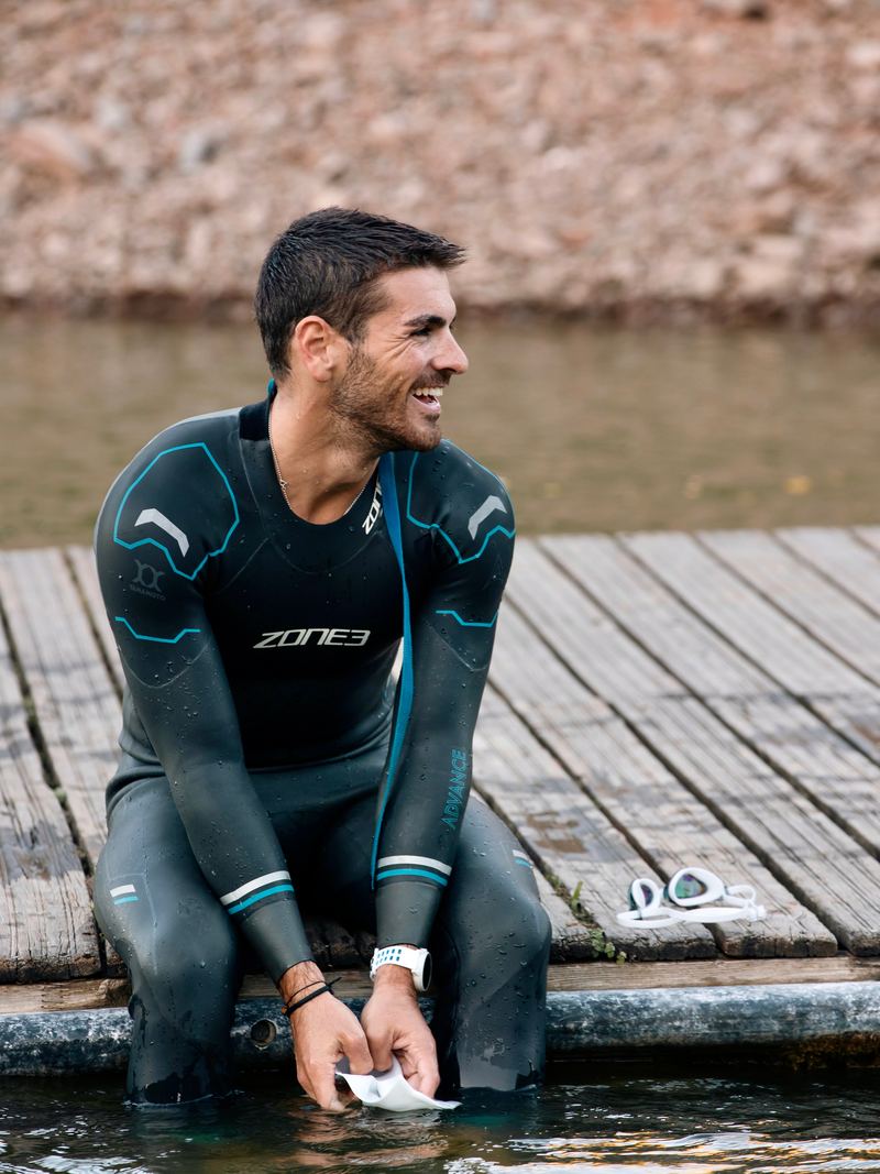 Gonçalo de fato de neoprene, sentado num pontão, a sorrir